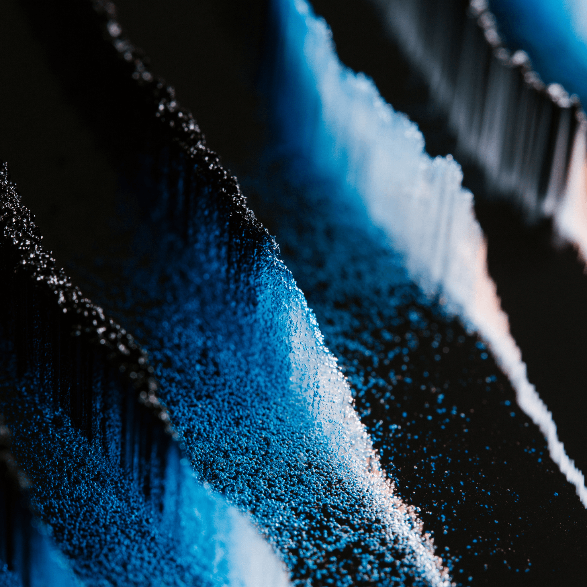 Macro photograph of blue and black pigment in diagonal ridges